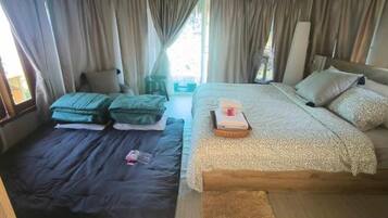 A room with a bed, a smaller bed, and a window with curtains.
