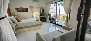 A bedroom with two beds, a desk, and a balcony with a view. - Tuabaandin (Mae Rim)