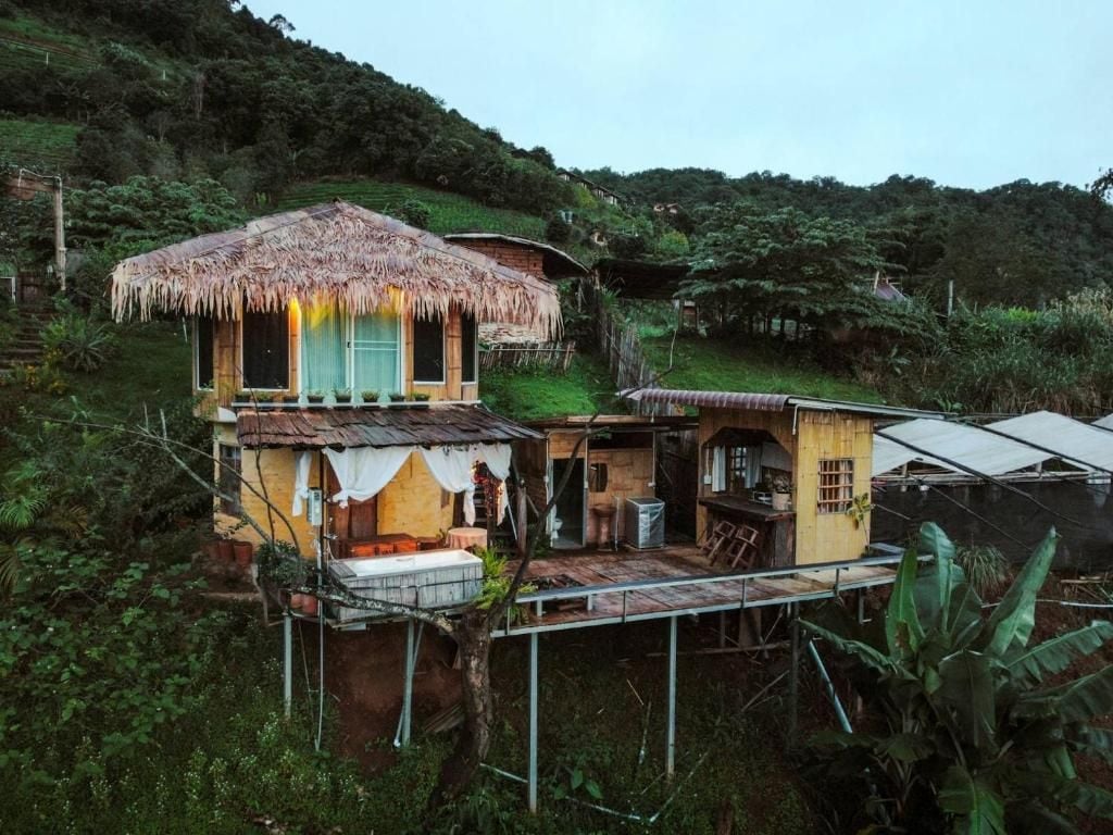 A rustic house with a thatched roof, a balcony, and a small garden area.
