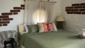 A bedroom with a bed, a bedside table, a lamp, and a window with curtains.