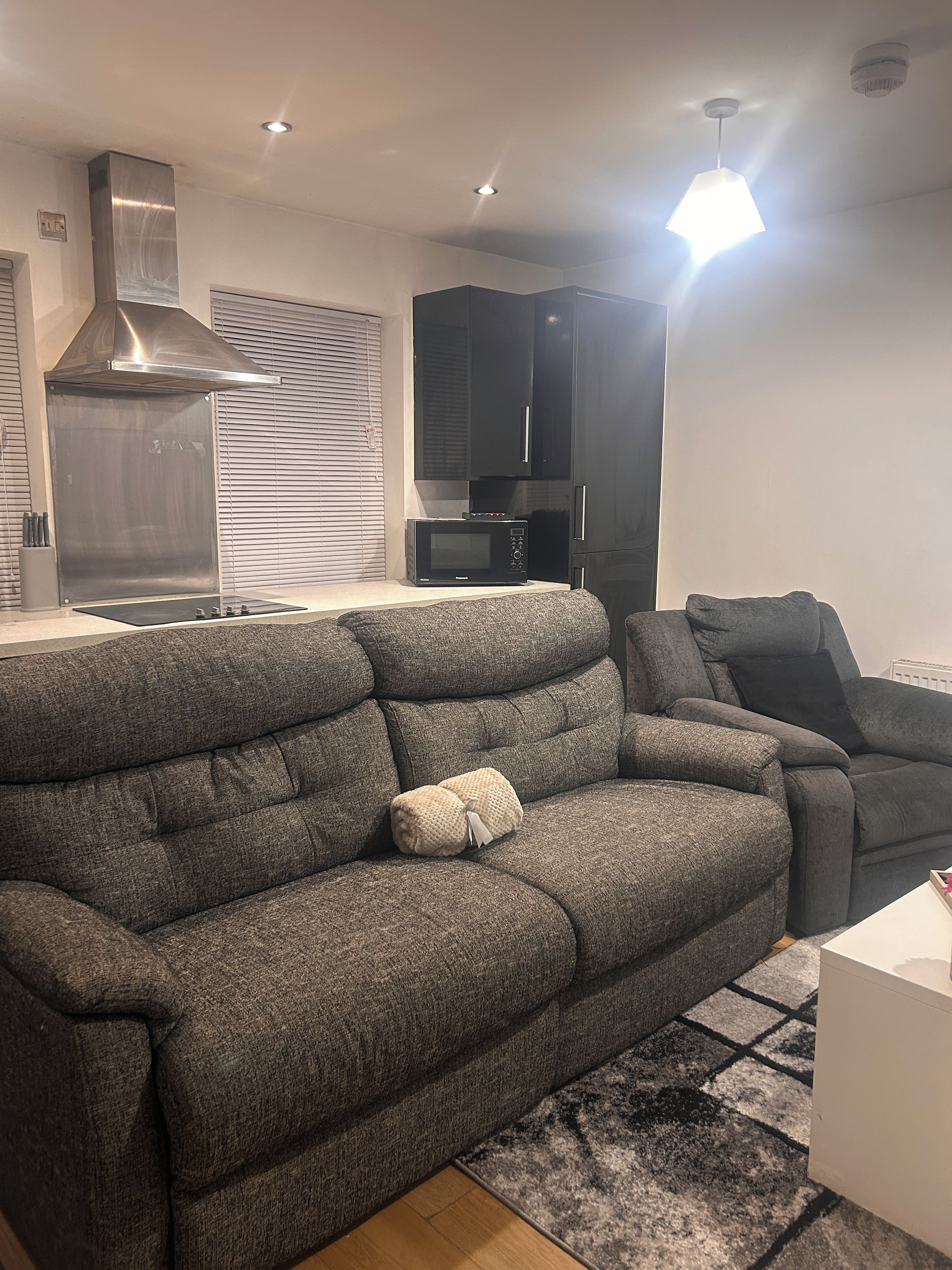 A modern living room with a grey sofa, a flat-screen TV, and a built-in microwave.