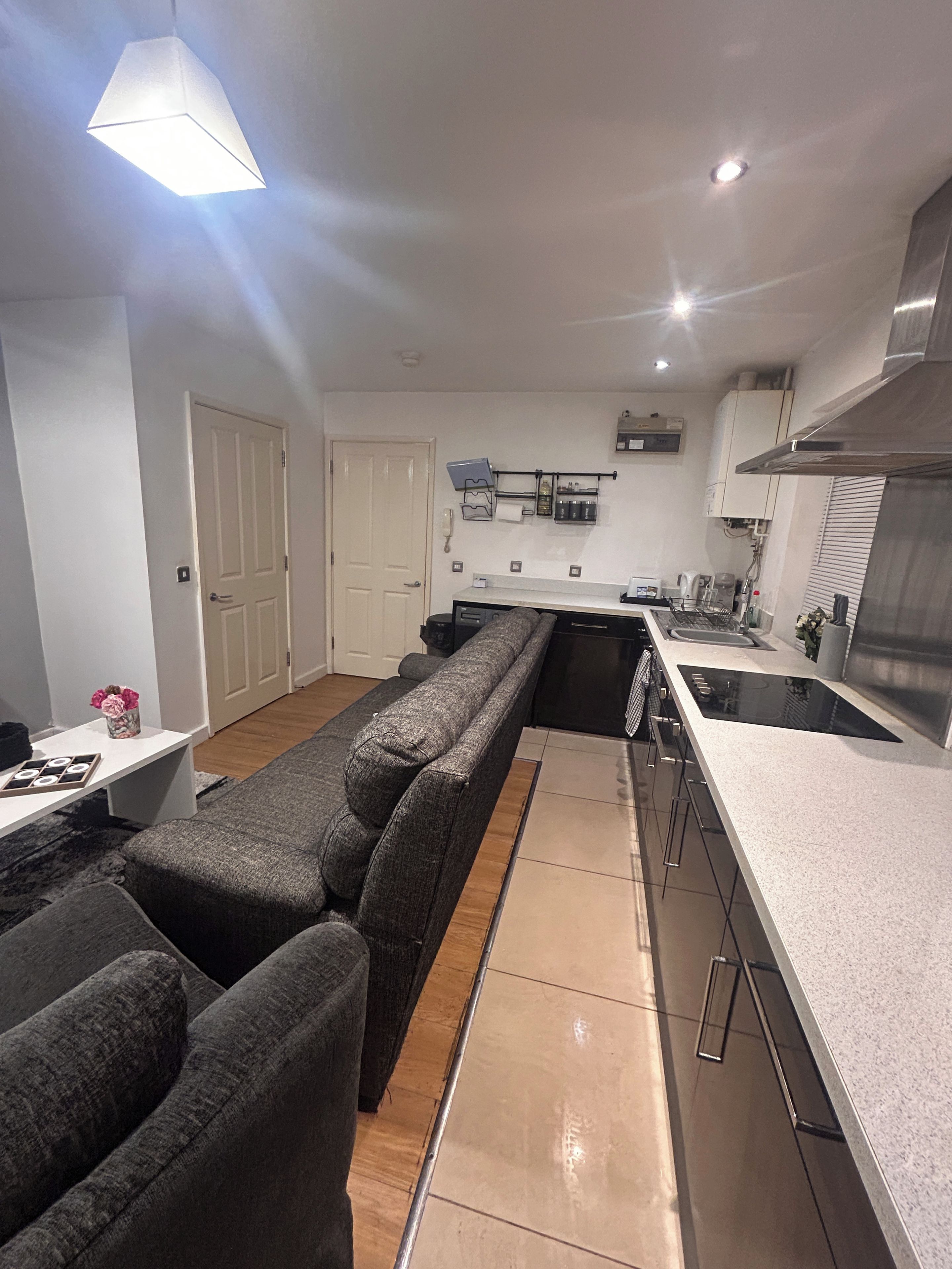 A modern kitchen with a built-in oven, a dining area with a long table, and a sofa.