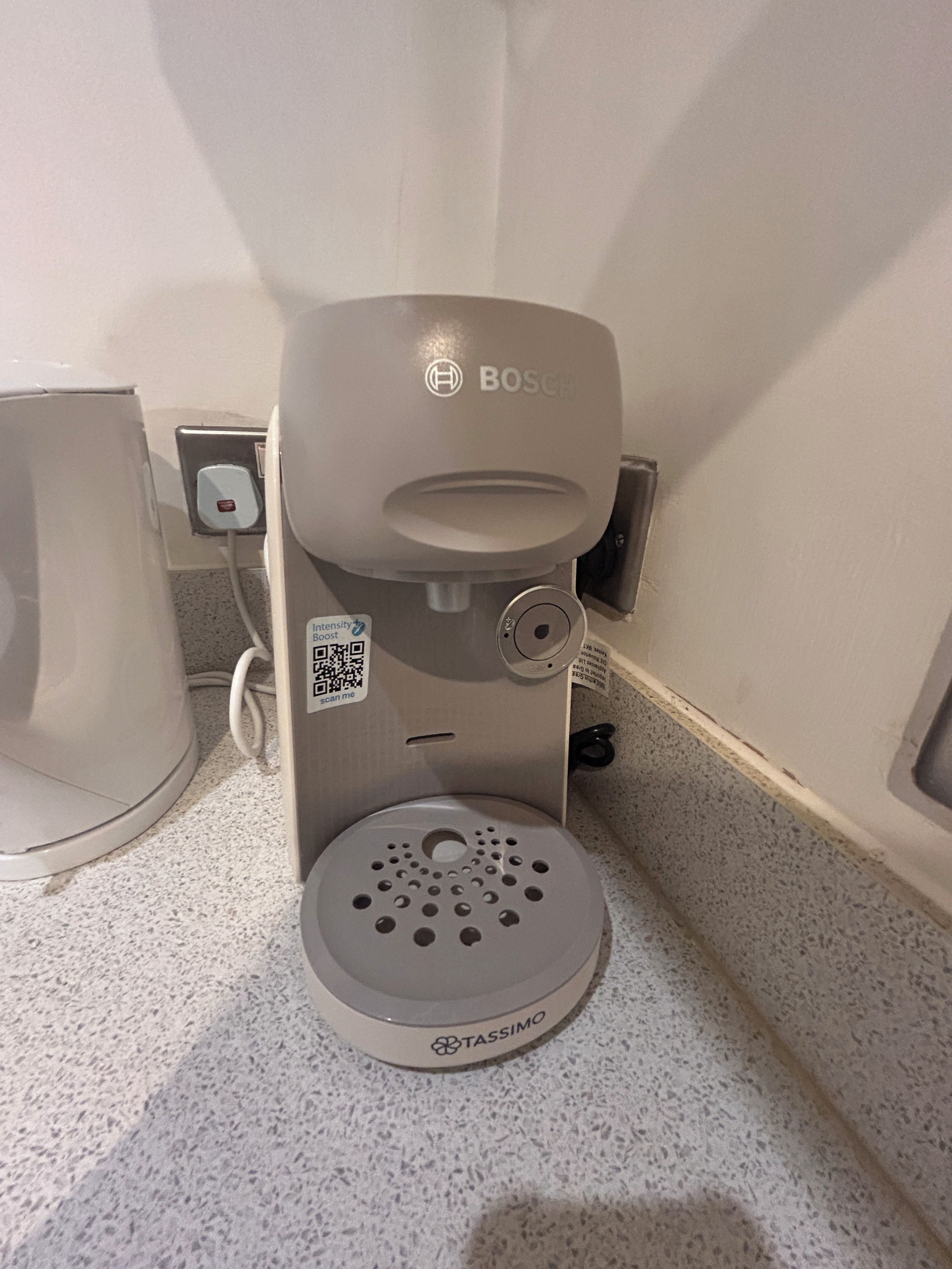A coffee machine with a QR code and a Tassimo pod holder.