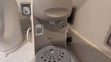 A coffee machine with a QR code and a Tassimo pod holder.