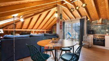 Un acogedor dormitorio en el ático con comedor, sofá y cocina.