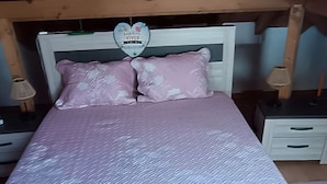 A bed with a textured white mattress, pink pillows, and a red blanket. - 'Waves Inn' Surf, Beach & Relax. With Wi-Fi (Silveira)