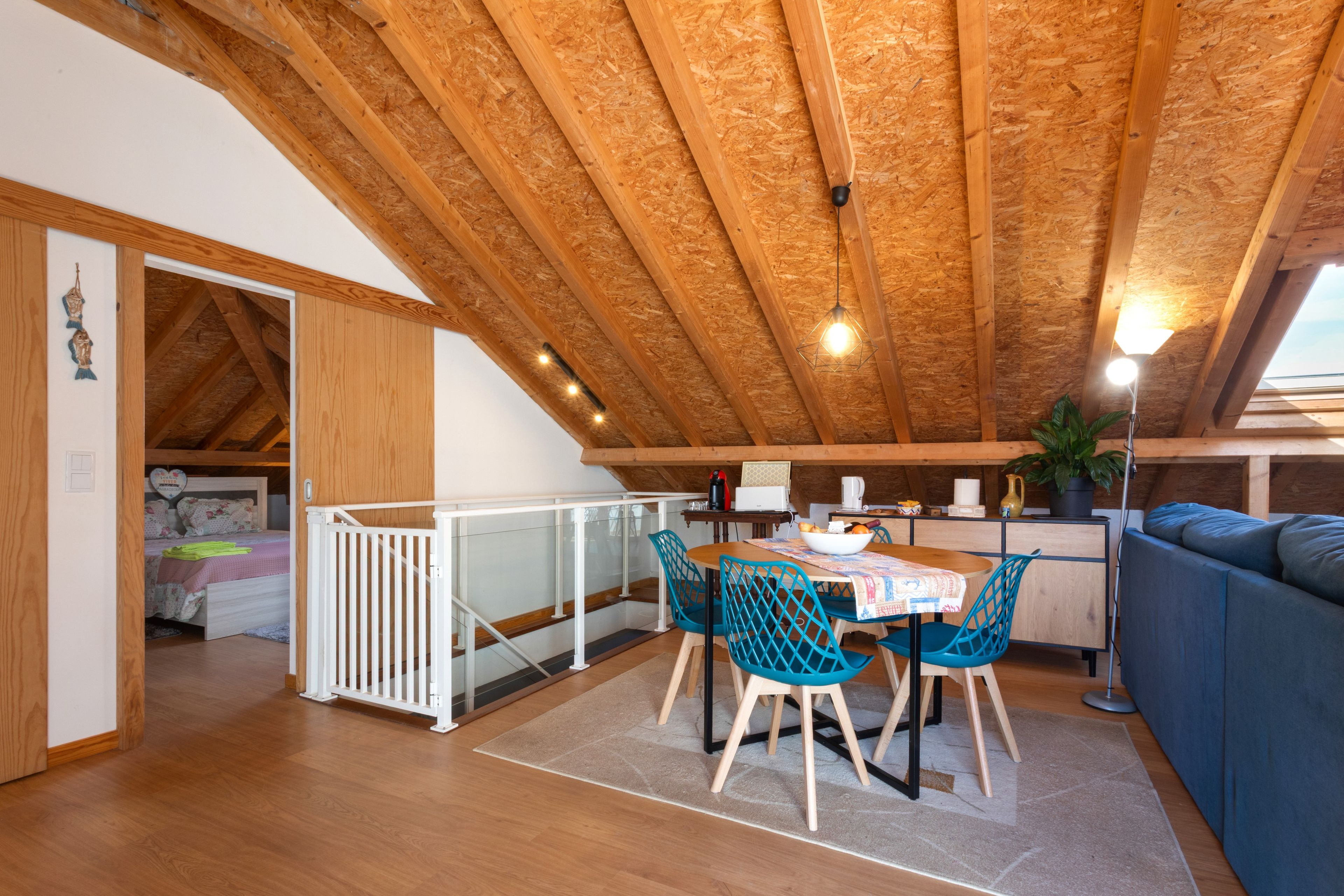 Acogedor dormitorio en ático con comedor, sofá y cama con ropa de cama floral.