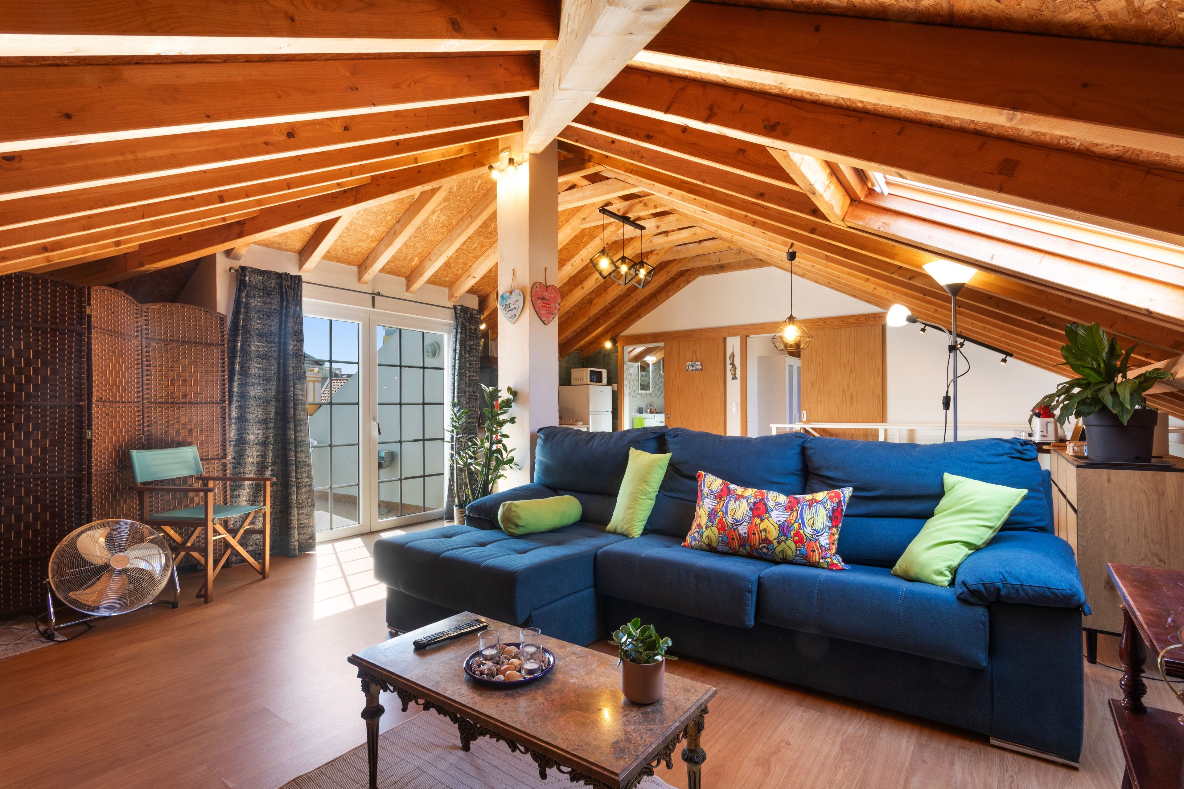 Una sala acogedora con un sofá seccional azul, una mesa de centro de madera y un ventilador.