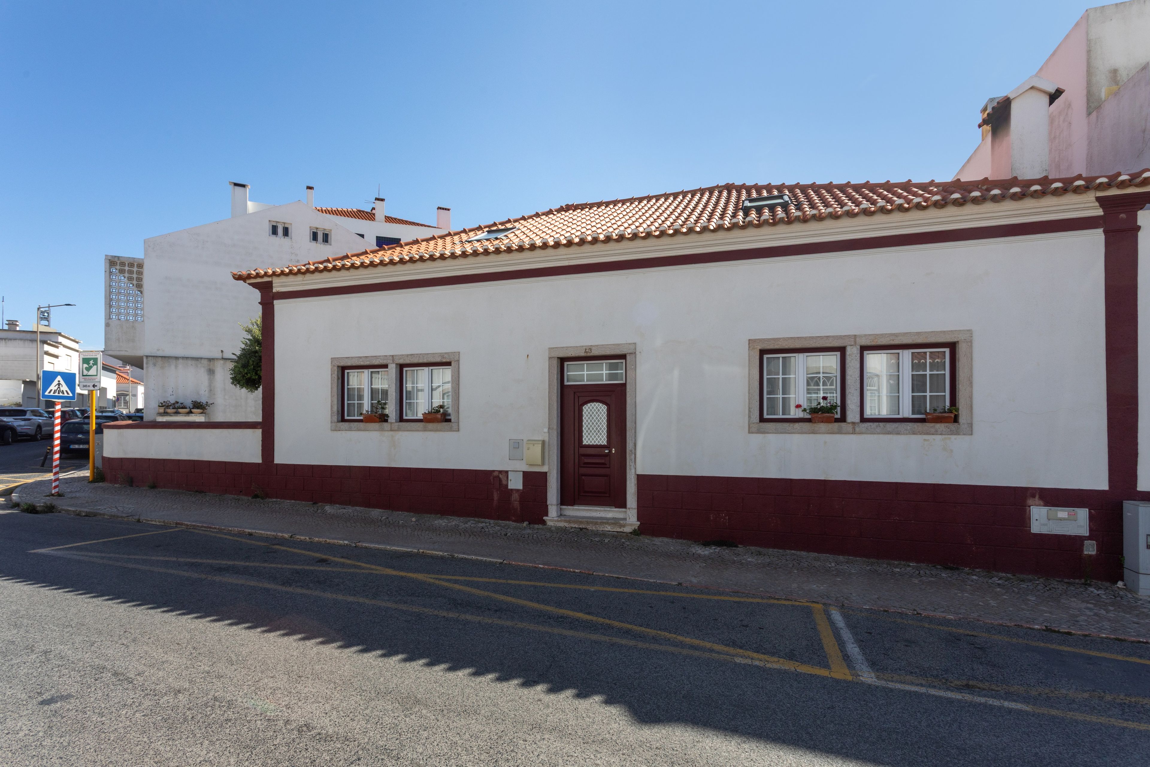 Un edificio con puerta roja, paredes blancas y techo de tejas.