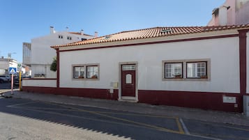 Un edificio con puerta roja, paredes blancas y techo de tejas.