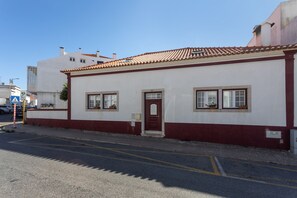 A building with a red door, white walls, and a tiled roof.