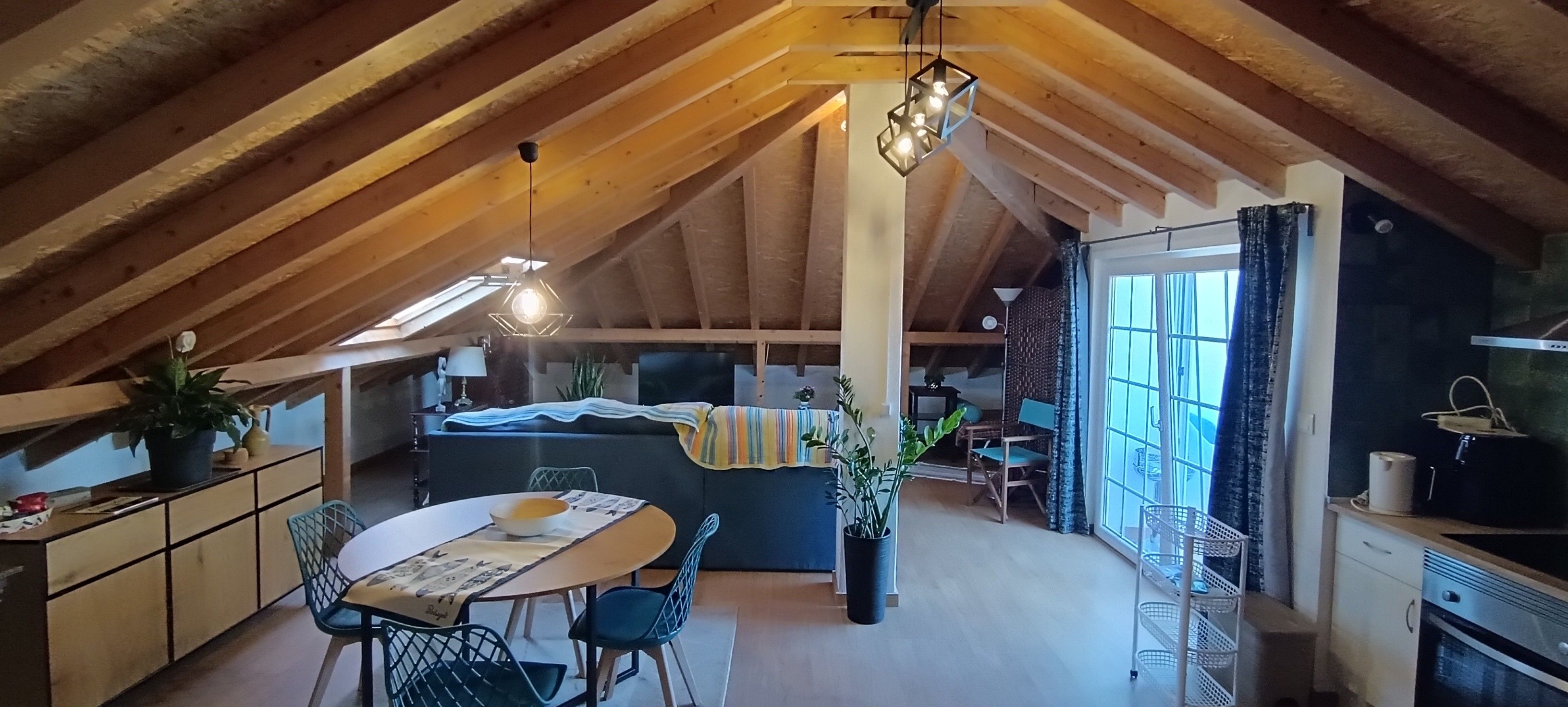 Un ático acogedor con una mesa de comedor, sillas, un sofá y una zona de cocina.