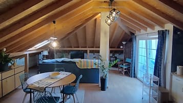 Un ático acogedor con una mesa de comedor, sillas, un sofá y una zona de cocina.