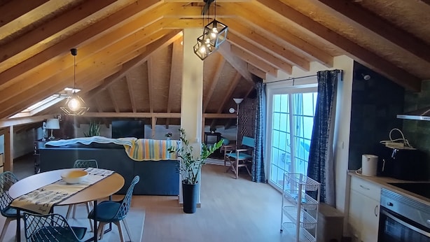 A cozy attic space with a dining table, chairs, a sofa, and a kitchen area. - 'Waves Inn' Surf, Beach & Relax. With Wi-Fi (Silveira)