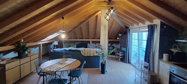 Un ático acogedor con una mesa de comedor, sillas, un sofá y una zona de cocina.