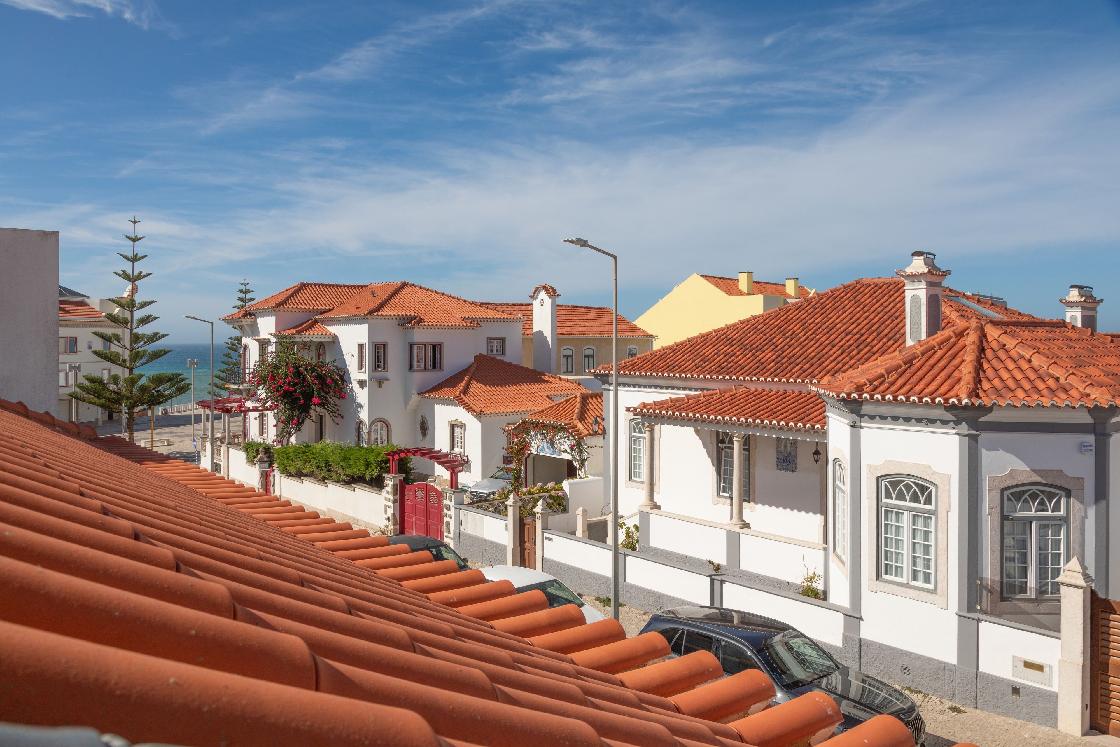 Una calle costera con tejados de tejas color terracota, edificios blancos y cielo despejado.