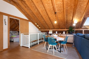 A cozy attic room with a dining area, a sofa, and a bed.