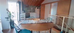 Un comedor con una mesa redonda, sillas, un tazón y una planta en maceta.