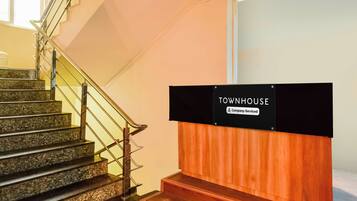 Una escalera con barandilla, un cartel que indica 'TOWNHOUSE Company-Serviced' y un panel de madera.