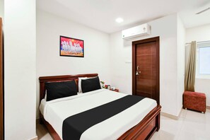 Un dormitorio con una cama, un cuadro, un aire acondicionado, una puerta y una ventana.
