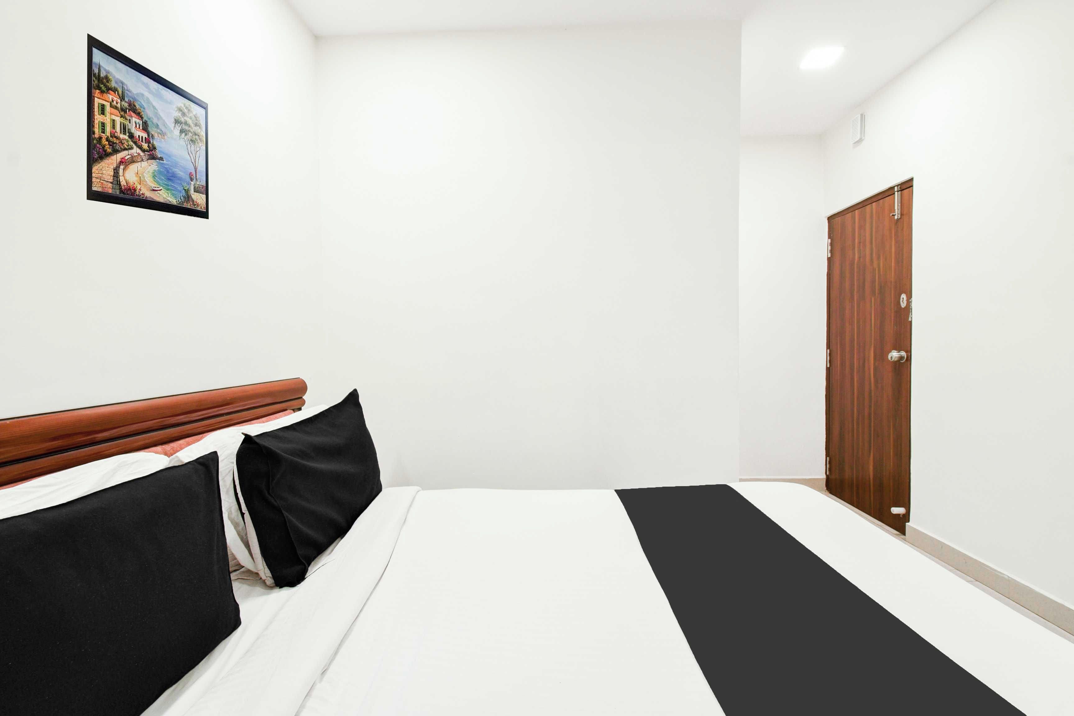 Habitación de hotel con cama, cabecero de madera, un cuadro en la pared y un armario.