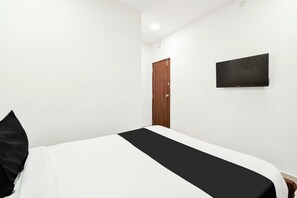 A hotel room with a bed, a television mounted on the wall, and a wooden door. - Townhouse Durgam Cheruvu Metro Station (Hyderabad)