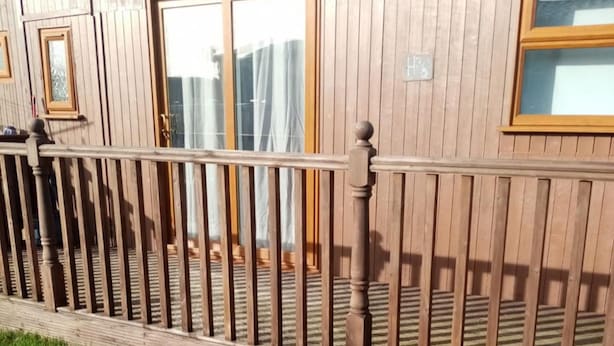 A wooden building with a balcony and windows.