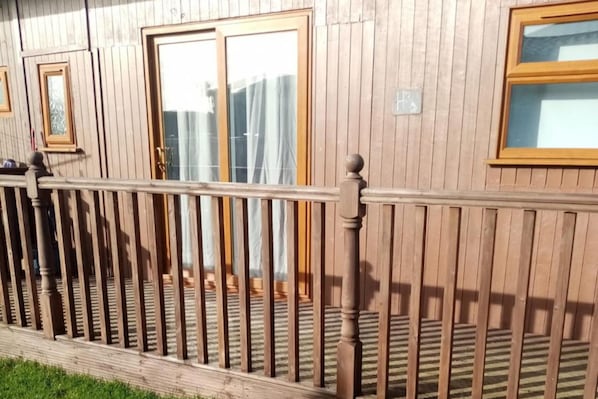 A wooden building with a balcony and windows.