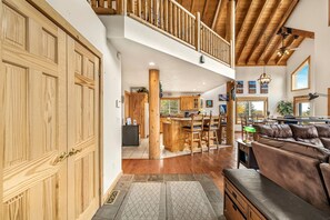 Un vaste espace de vie doté d’un plafond en bois, un coin repas avec des chaises en bois, une cuisine avec des meubles en bois et une grande porte en bois.