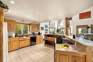 A spacious kitchen with wooden cabinets, a dishwasher, and a large island with a stove. - Beautiful Lakefront Cabin with Private Dock near Yellowstone in Island Park, Idaho (Island Park)