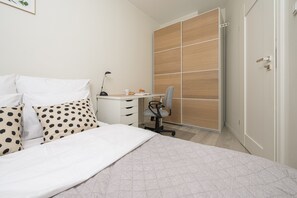 A bedroom with a bed, a desk, a chair, and a wardrobe. - Wileńska P&O Apartments (Warszawa)