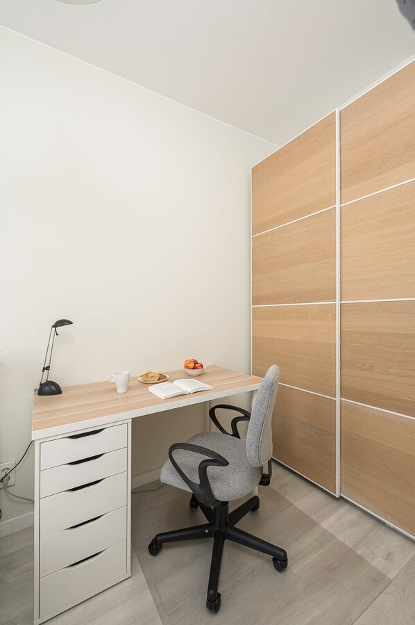 A workspace with a desk, chair, lamp, and a wall with a geometric pattern.