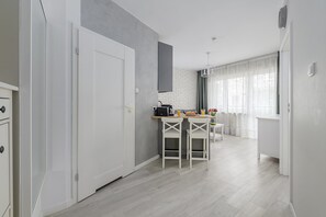 A modern kitchen with a white door, a breakfast bar, and a dining area with two chairs.