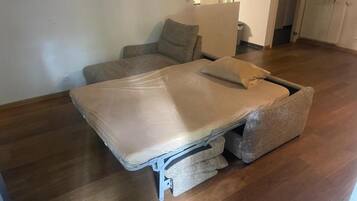 Een kamer met een bed, een stoel en een klein tafeltje.