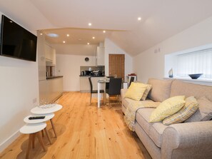 A modern living space with a kitchen, dining area, and a sofa with cushions. - Fishermans Loft (St Austell)