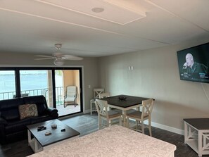 A living room with a sofa, coffee table, dining table, chairs, and a TV. - Bay to Gulf Townhouse on Manasota Key (Englewood)