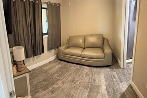A room with a beige leather sofa, a lamp, and curtains. - Bay to Gulf Townhouse on Manasota Key (Englewood)