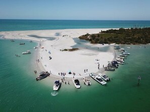 An aerial view of a beach with boats docked along the shore and people walking on the sand. - Bay to Gulf Townhouse on Manasota Key (Englewood)
