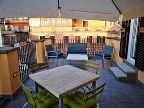Un espace extérieur aménagé en terrasse, avec une table et des chaises, un canapé et une rambarde.