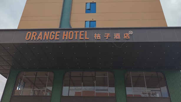 Un edificio de hotel con un letrero que dice 'Orange Hotel' y un toldo verde.