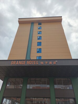 Un edificio de hotel con un letrero que dice 'Orange Hotel' y un toldo verde.