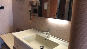Un baño con lavabo, espejo, toallero y un papel en la pared.