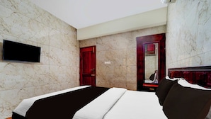 A hotel room with a bed, a TV mounted on the wall, a wooden door, and a mirror. - Townhouse Gandhipuram Central Bus Stand (Coimbatore)