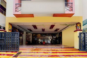 A hotel entrance with a tiled floor, a central staircase, and a decorative ceiling.