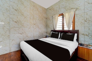 A hotel room with a large bed, wooden headboard, and a window with curtains. - Townhouse Gandhipuram Central Bus Stand (Coimbatore)