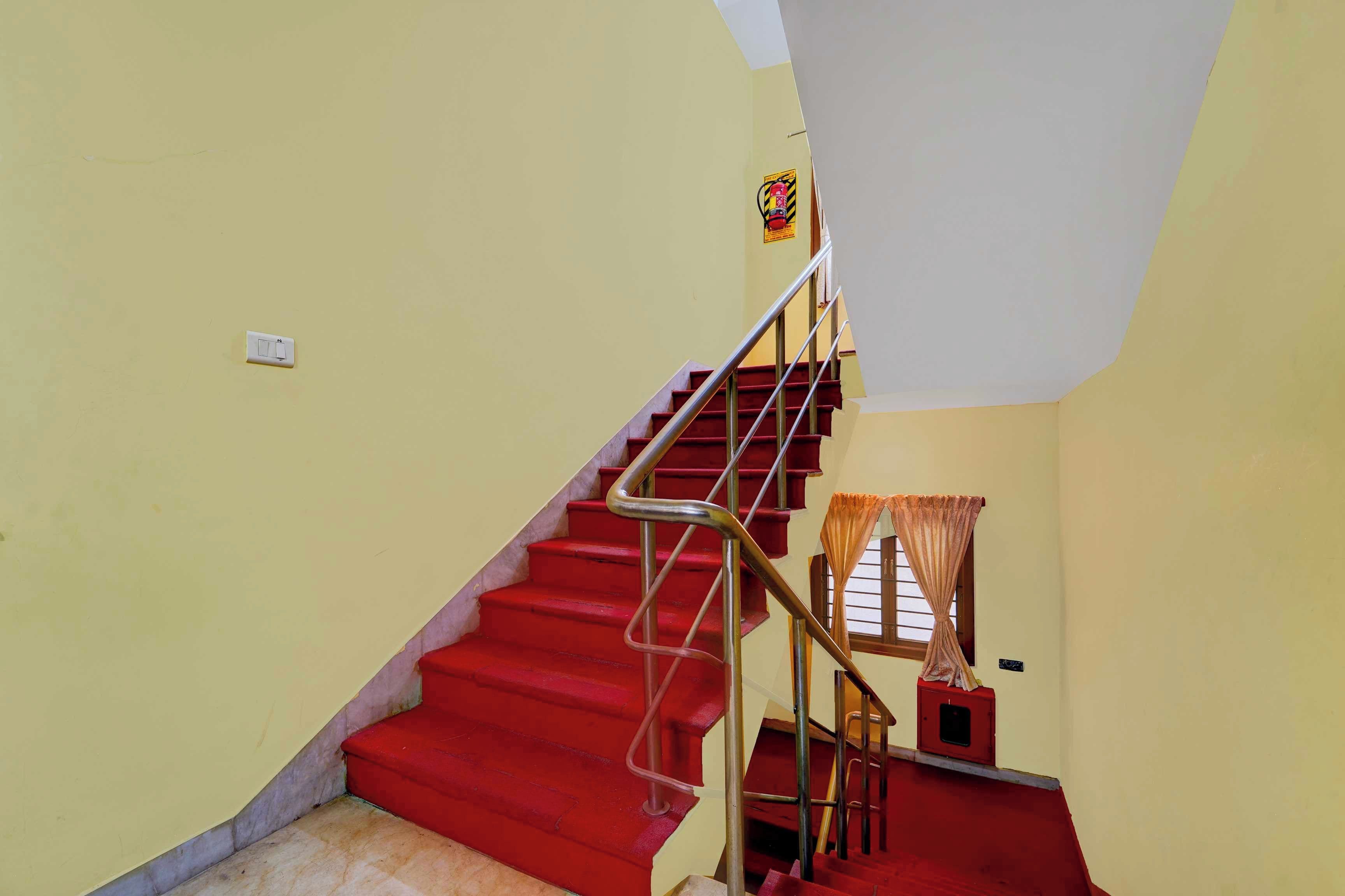 A staircase with red steps and metal railings leading to a landing.
