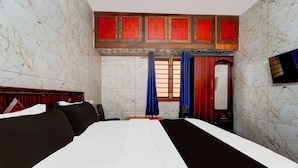 A hotel room with a bed, a wooden headboard, a wardrobe, and a window with curtains. - Townhouse Gandhipuram Central Bus Stand (Coimbatore)