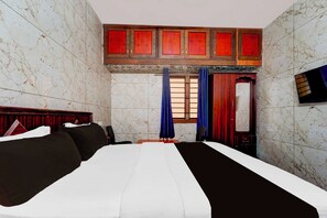 Habitación de hotel con cama, cabecero de madera, armario y ventana con cortinas.