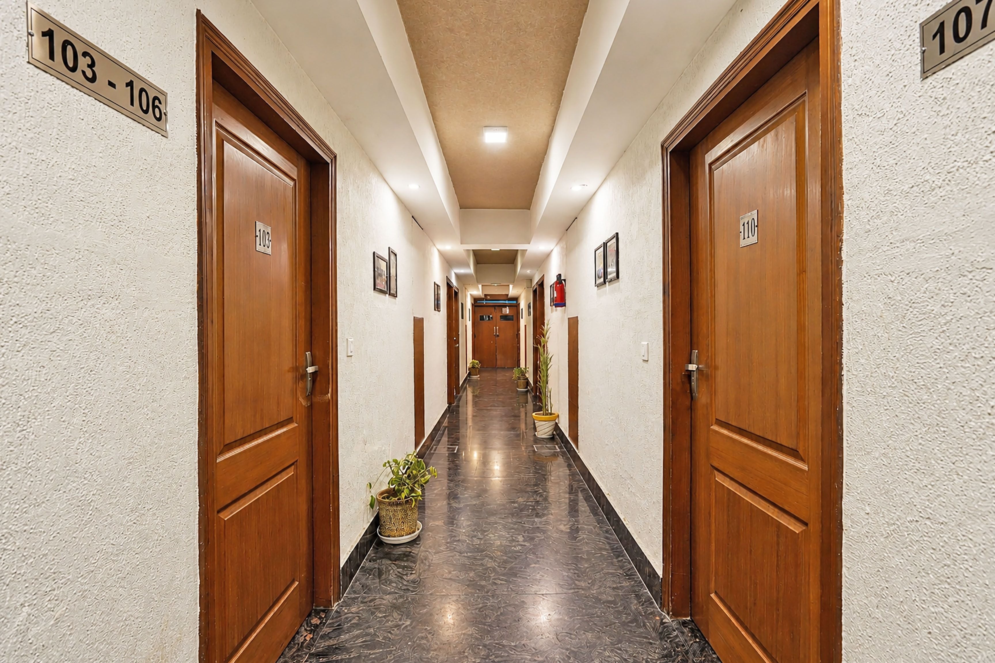 A hotel hallway with wooden doors numbered 103-106 and 110, leading to rooms.