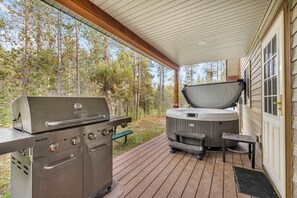 An outdoor deck with a Char-Broil grill and a hot tub. - Cozy Cabin Retreat with Hot Tub & Fire Pit for Summer in Island Park, Idaho (Island Park)